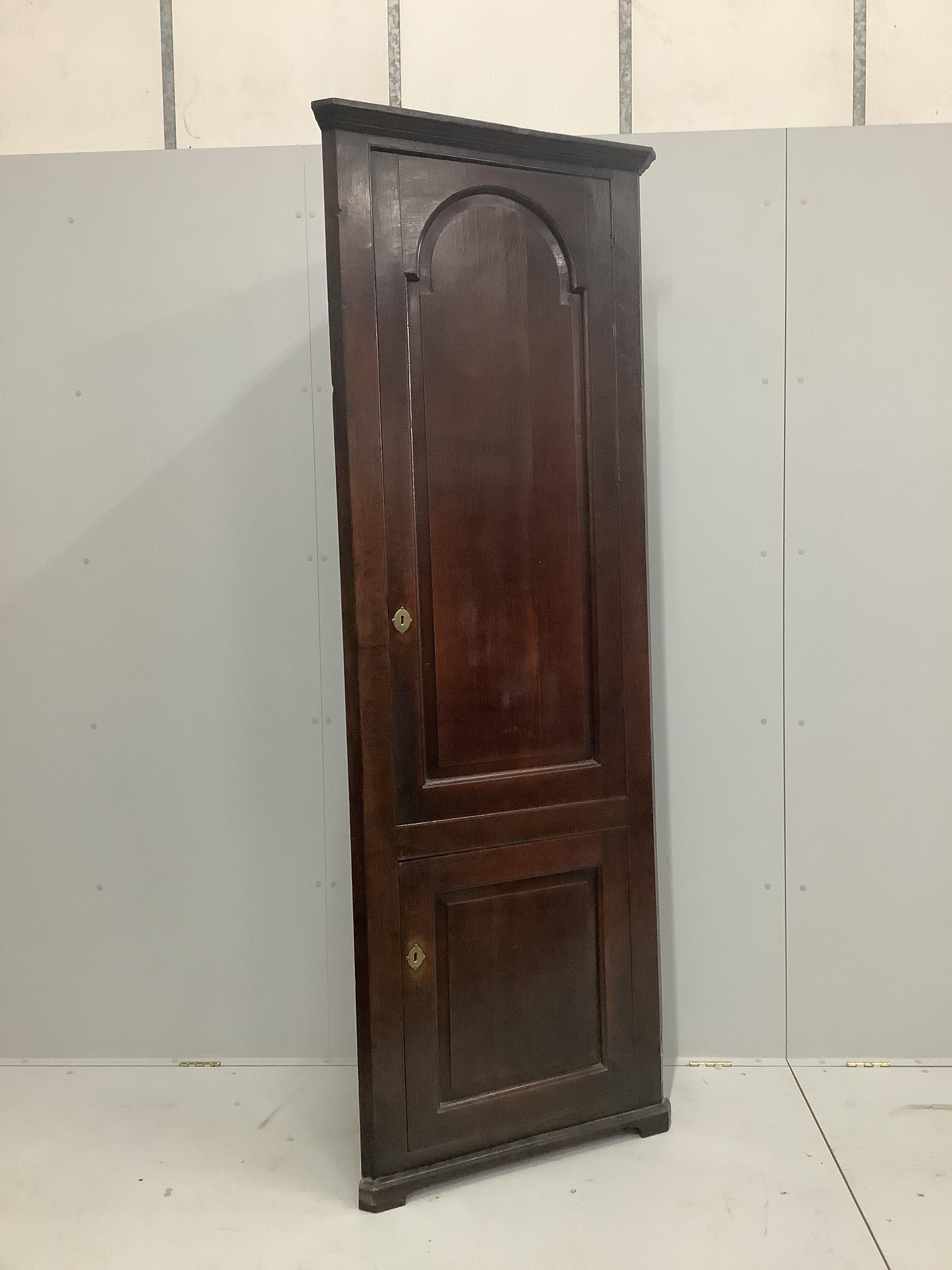 A George III free standing oak corner cupboard, with fielded panelled doors and shelved interior, width 80cm, height 223cm